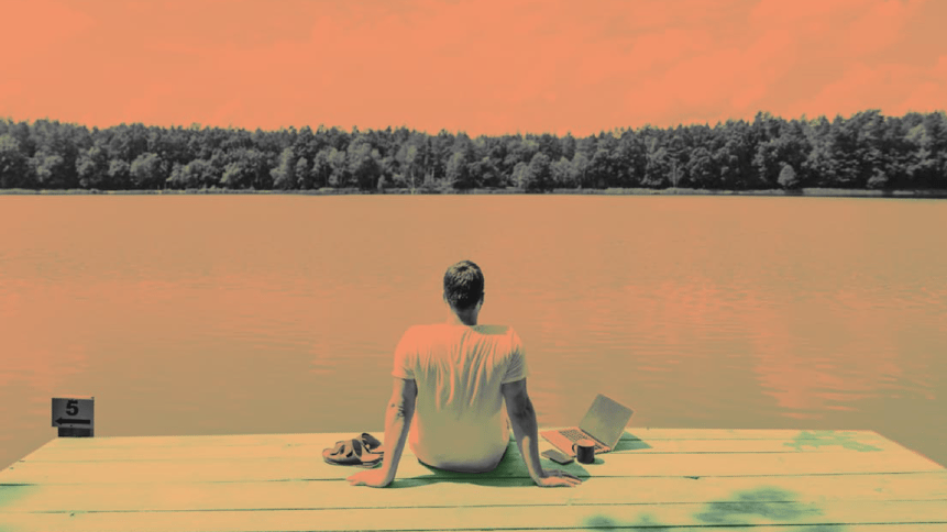 Man sitting on a dock facing a lake